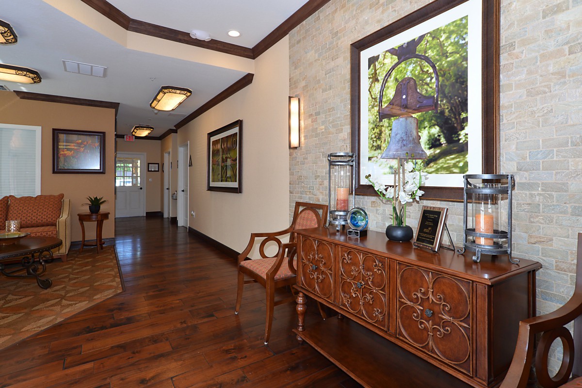 A warmly lit hallway with elegant wooden flooring, featuring decorative furniture and artwork.