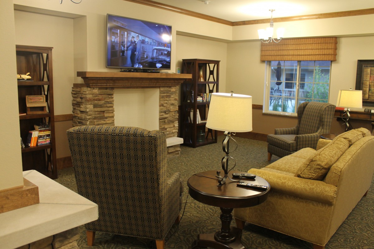 A cozy living room with a fireplace, comfortable seating, and a television mounted on the wall.