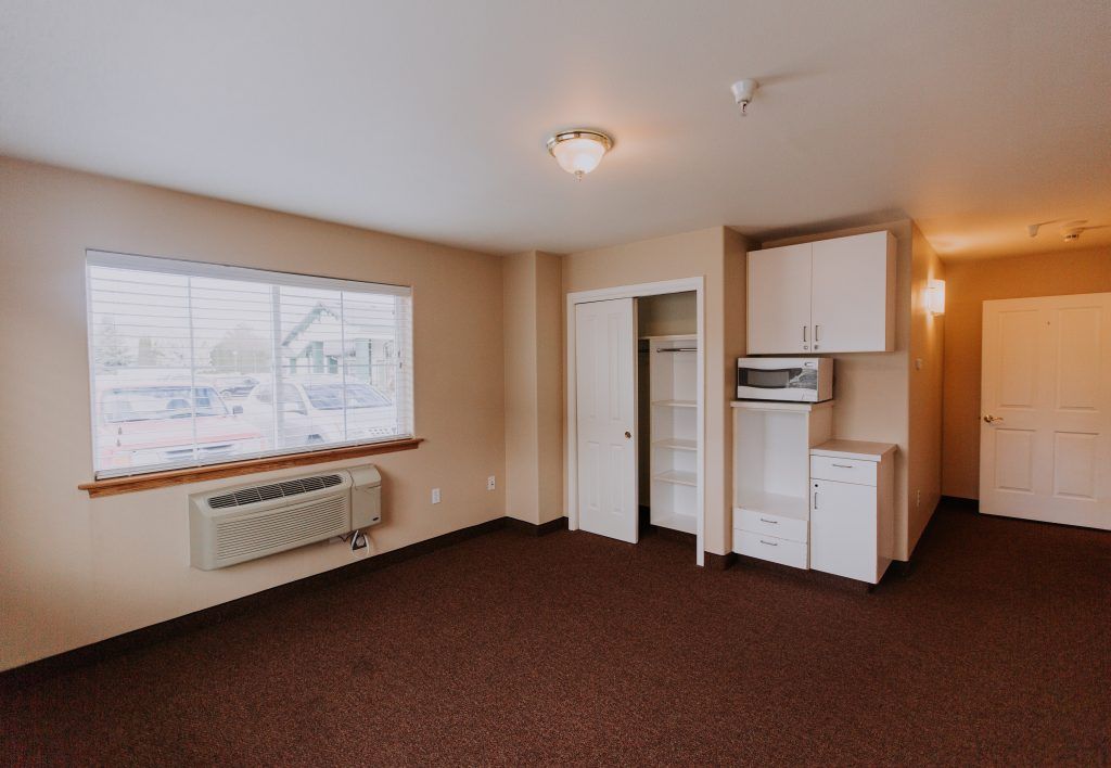 A small apartment room with a kitchenette and window view.