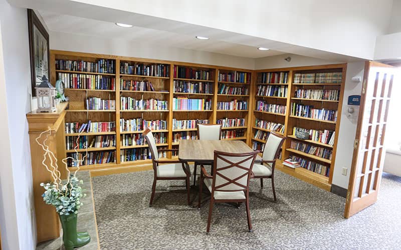A cozy library corner with bookshelves, a table, and chairs for studying.