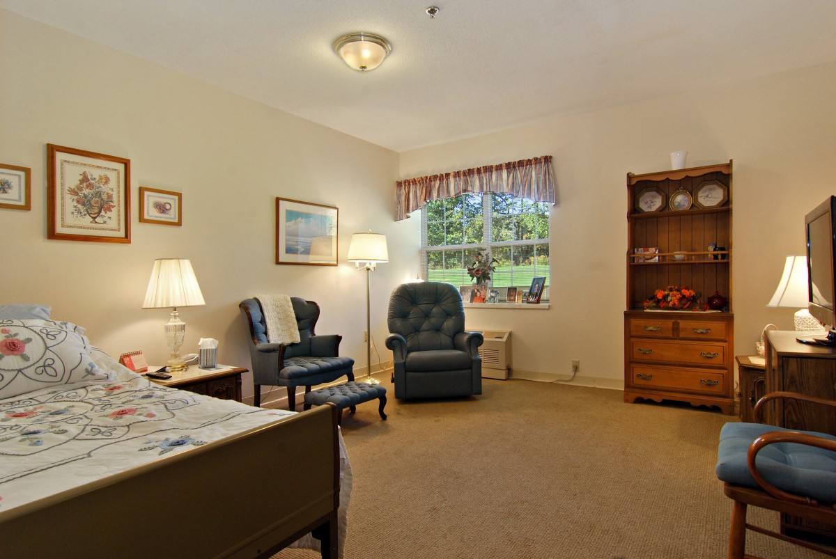 A cozy living room with armchairs, a lamp, and a window view.