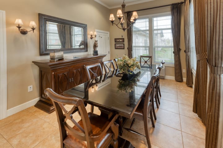 Elegant dining room with a large table, chairs, and a chandelier.