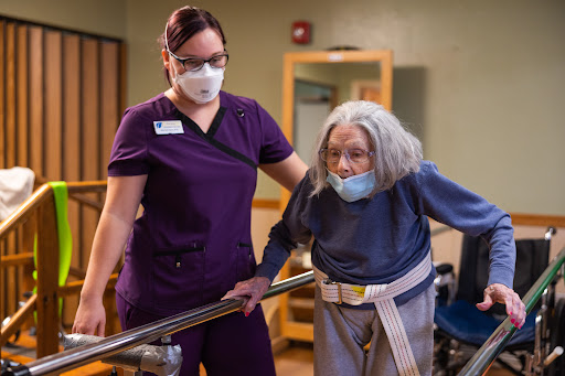 A healthcare worker assists an elderly woman during a rehabilitation session, highlighting the importance of supportive care.
