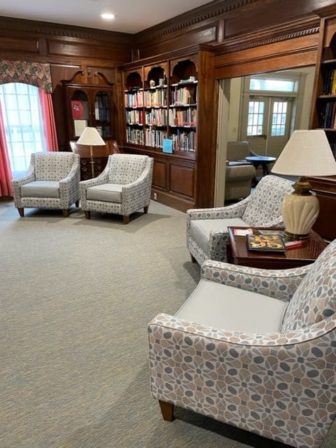 A cozy library room with armchairs and wooden bookshelves.