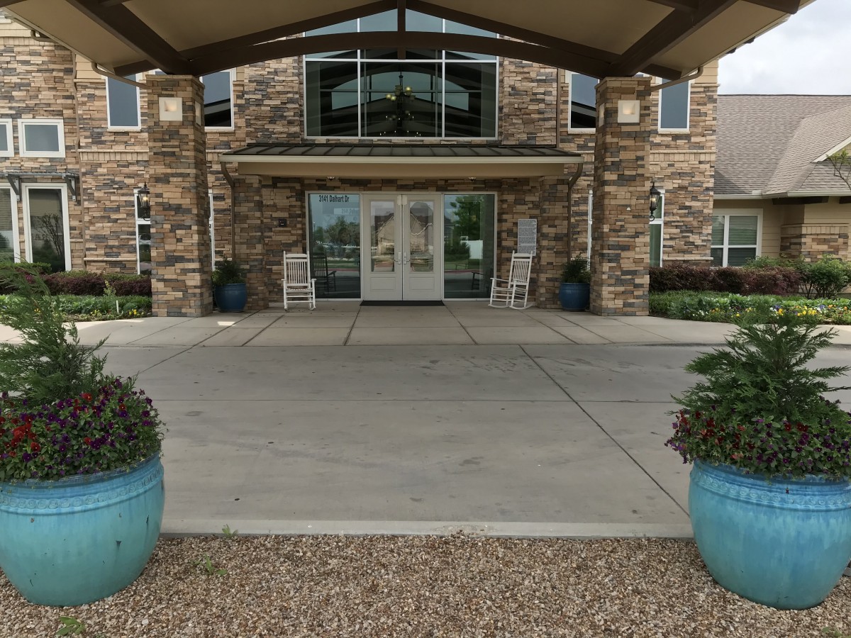 The entrance of a building with a stone facade and large planters.