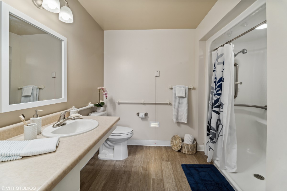 A well-organized bathroom featuring a sink, toilet, shower, and towels.