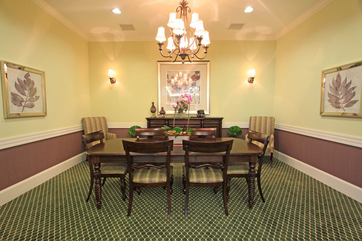 A well-appointed dining room with upholstered chairs, a polished table, and an elegant chandelier.