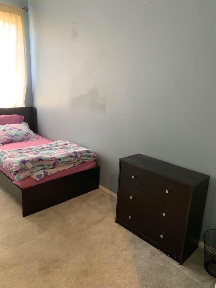 A minimalist bedroom with a single bed and a small dresser.