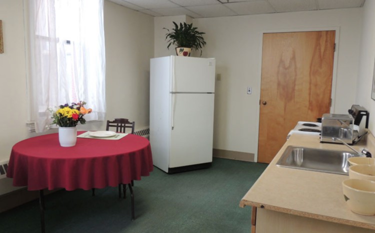 A small kitchen area with a refrigerator, table, and indoor plants.
