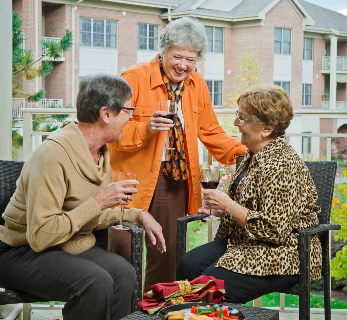 A group of senior women enjoying a conversation and drinks outdoors.