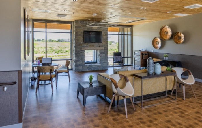 A modern living room with large windows, a central fireplace, and stylish furniture.