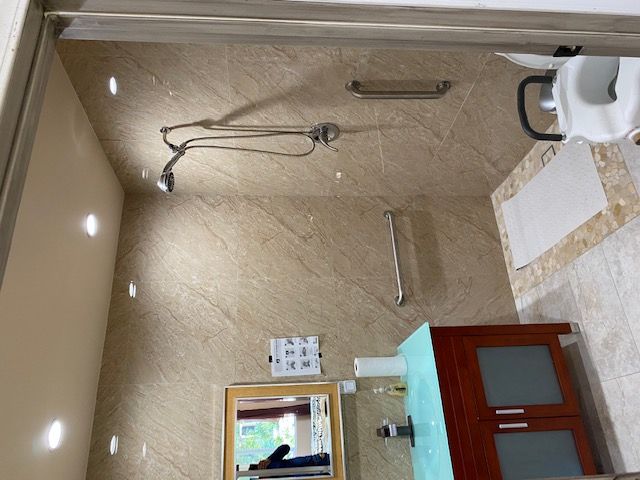 A modern bathroom with a shower area, glass door, and tile walls.