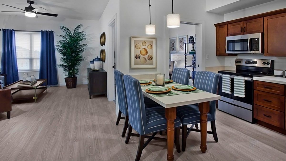 A modern dining room with a table set and striped chairs, illuminated by pendant lights.