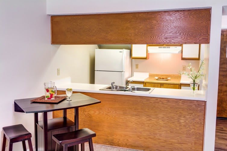 A cozy kitchen interior with a counter, refrigerator, and small dining area.