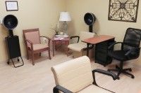 A small waiting room with chairs, a table, and a lamp.