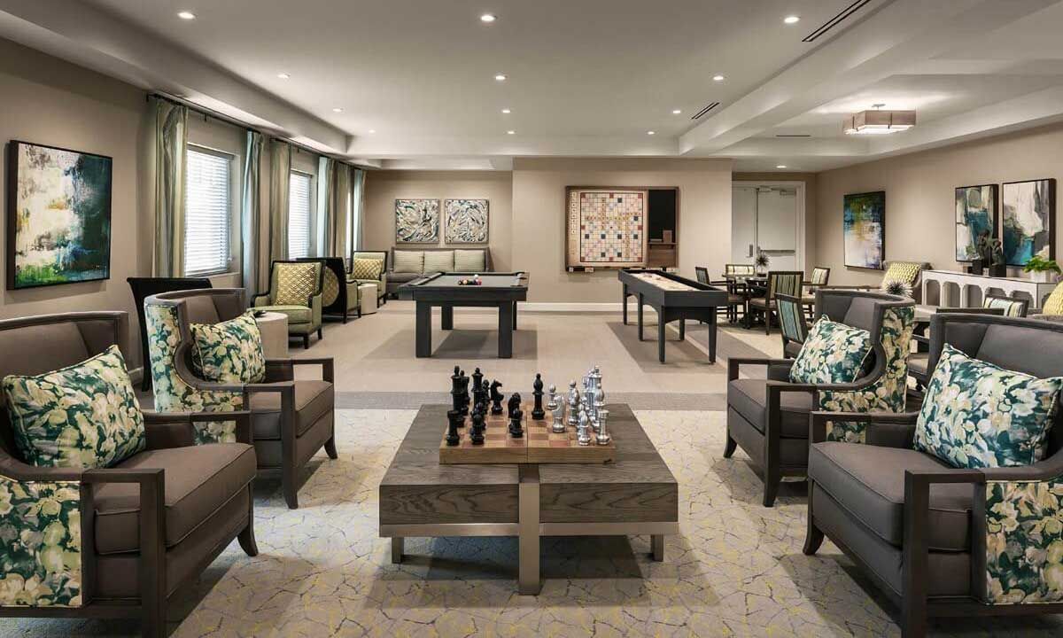 A luxurious game room featuring a chess board, foosball table, and elegant seating with modern decor and artwork.