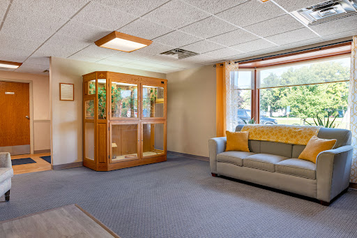 A cozy living room with a comfortable sofa and a display cabinet, illuminated by natural light from the window.