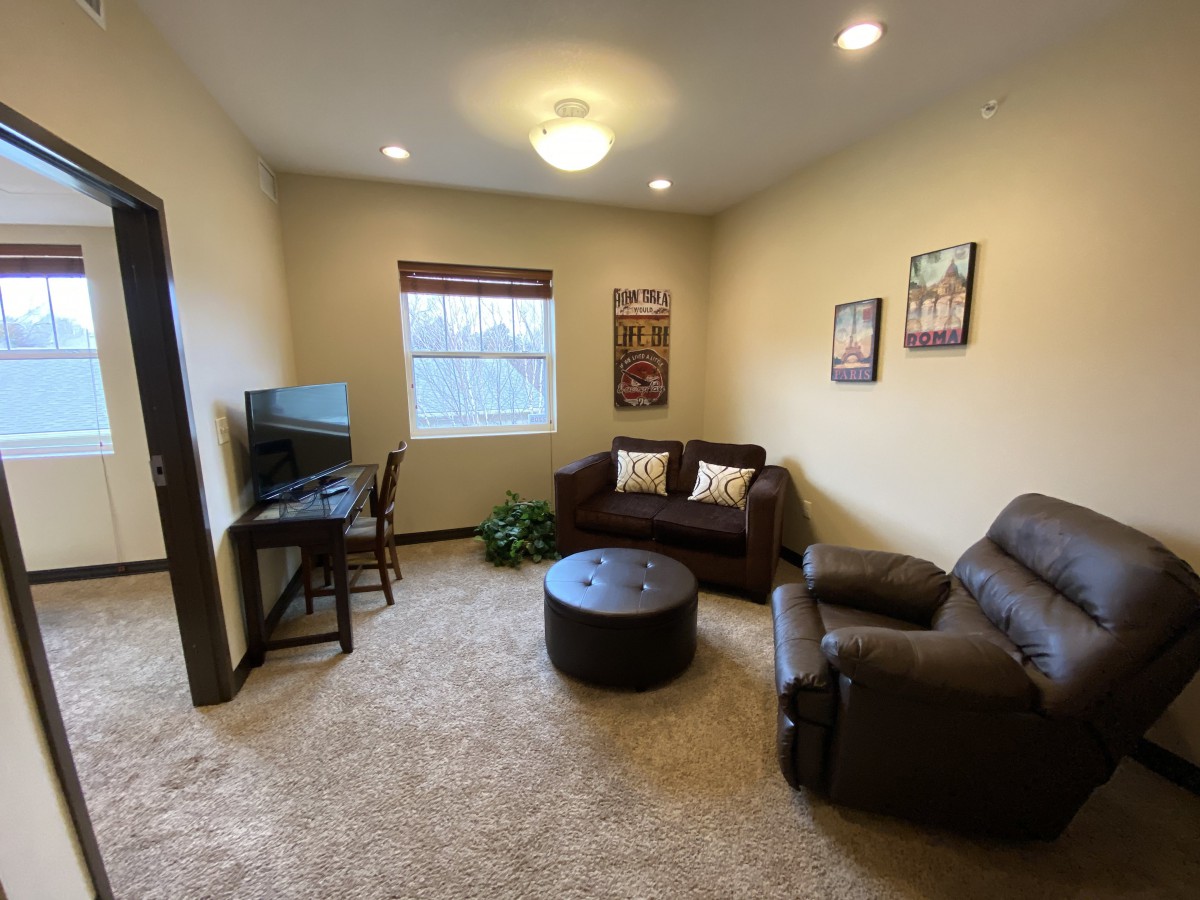 A cozy living room with a sofa, armchair, TV, and coffee table.