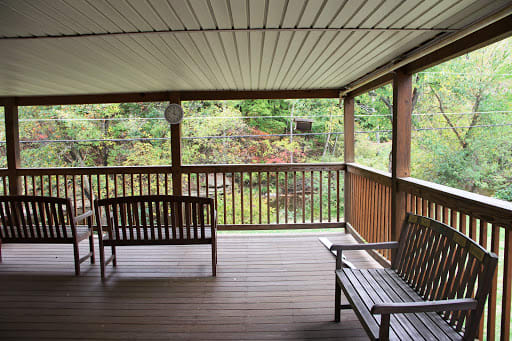 A peaceful covered porch with wooden seating overlooking a lush garden.