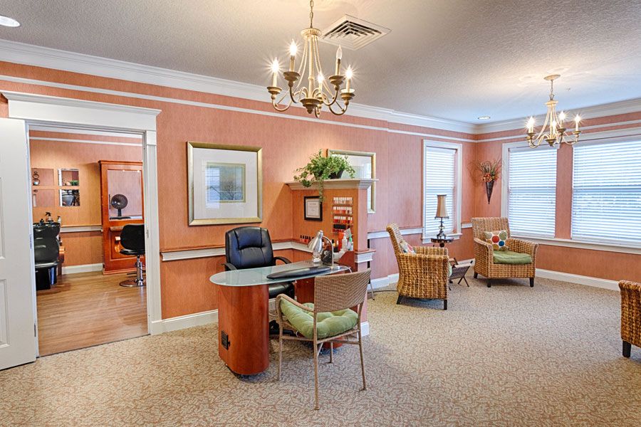 A warmly decorated office space with a central desk and seating area, adorned with artwork and light fixtures.