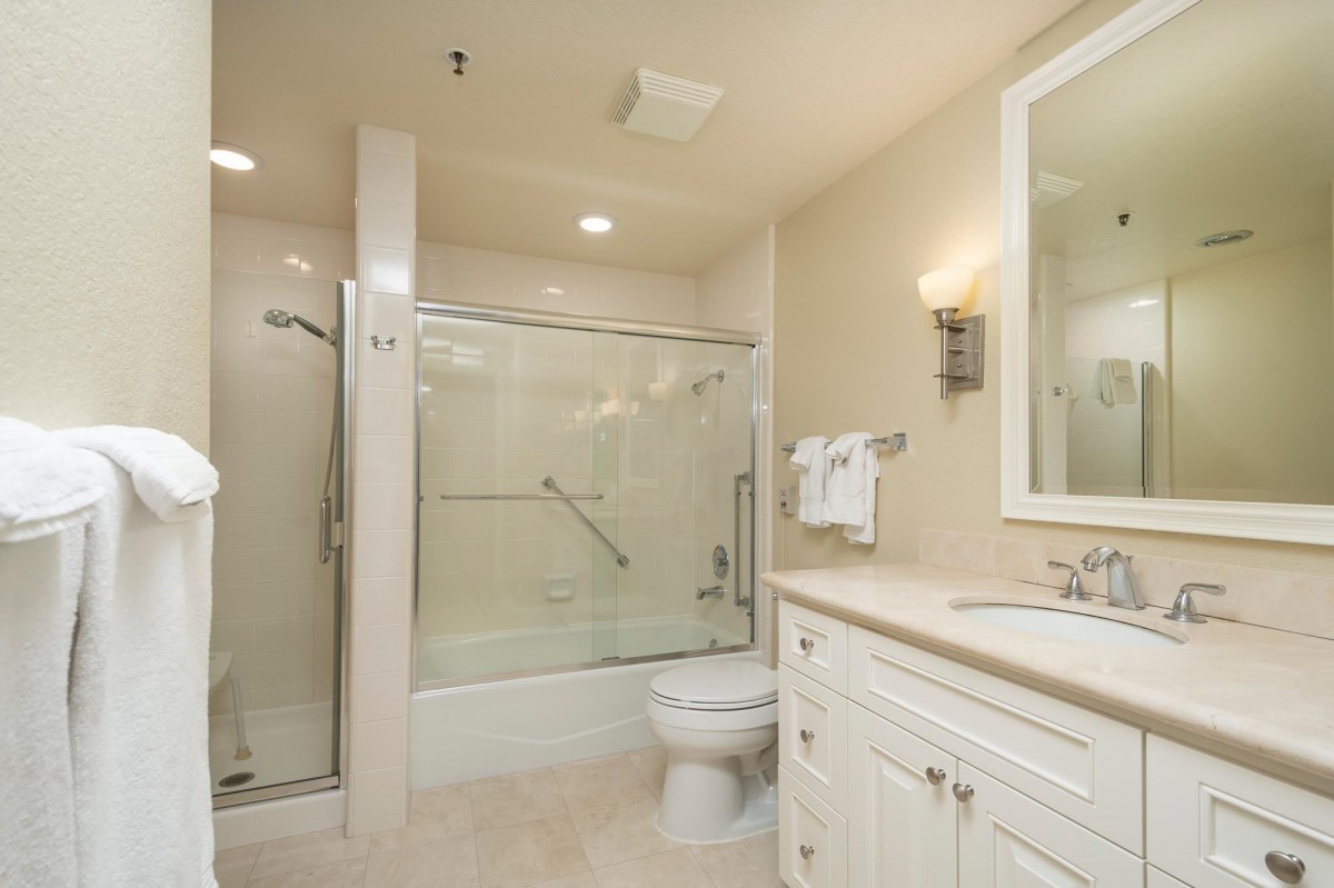 A clean and modern bathroom featuring a glass-enclosed shower, toilet, and vanity with a large mirror.