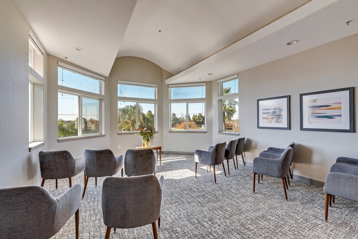 A bright meeting room with chairs arranged in rows and large windows providing a scenic view.
