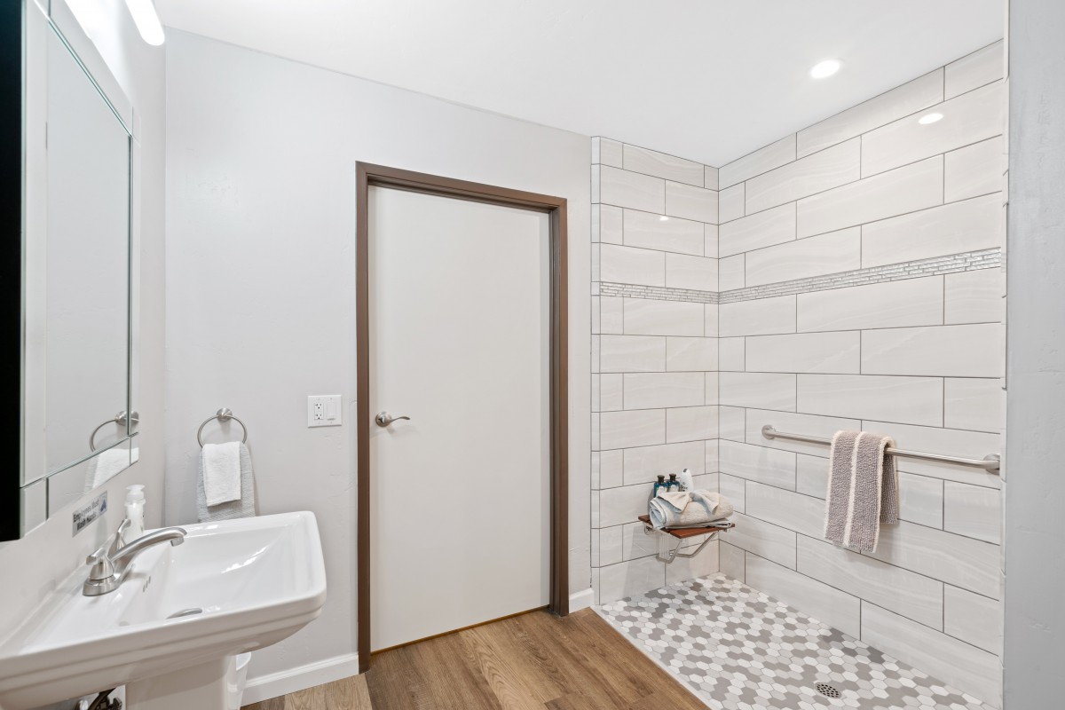 A modern minimalist bathroom featuring a walk-in shower and wooden flooring.