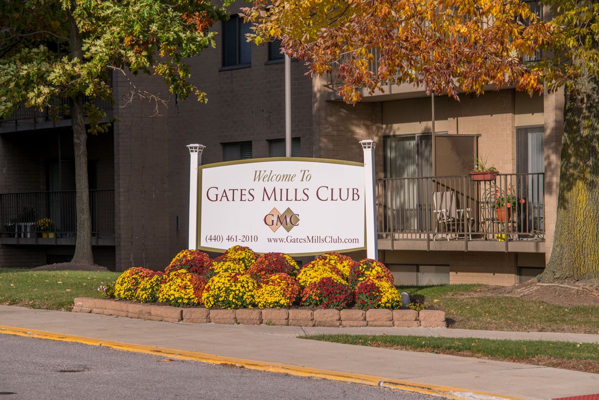 Sign for Gates Mills Club surrounded by autumn foliage and flowers.