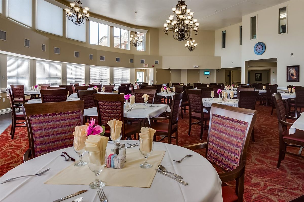 An elegant dining room with neatly arranged tables and chandeliers.
