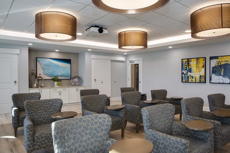 A modern waiting room with comfortable seating, contemporary lighting, and artwork on the walls.