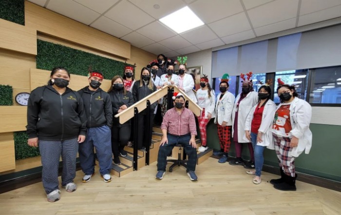 A group of people in festive attire and masks posing together in an office setting.