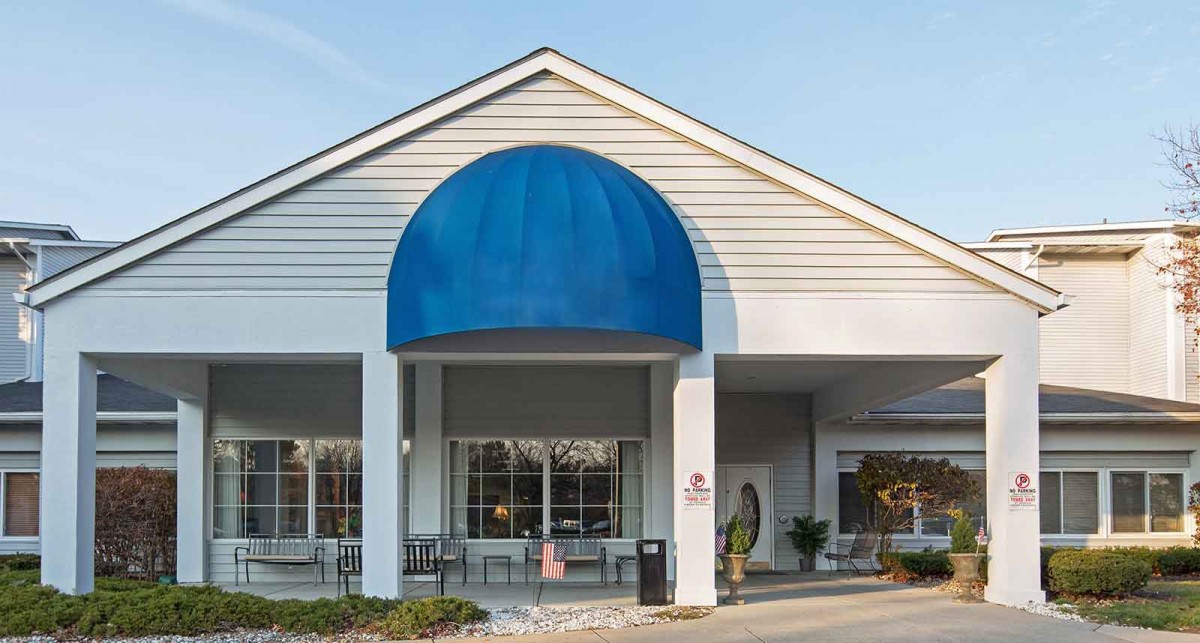 A building entrance with a blue awning and large windows.