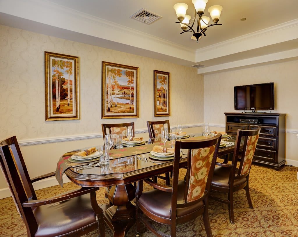 An elegant dining room featuring a polished wooden table, upholstered chairs, and framed artwork on the walls.
