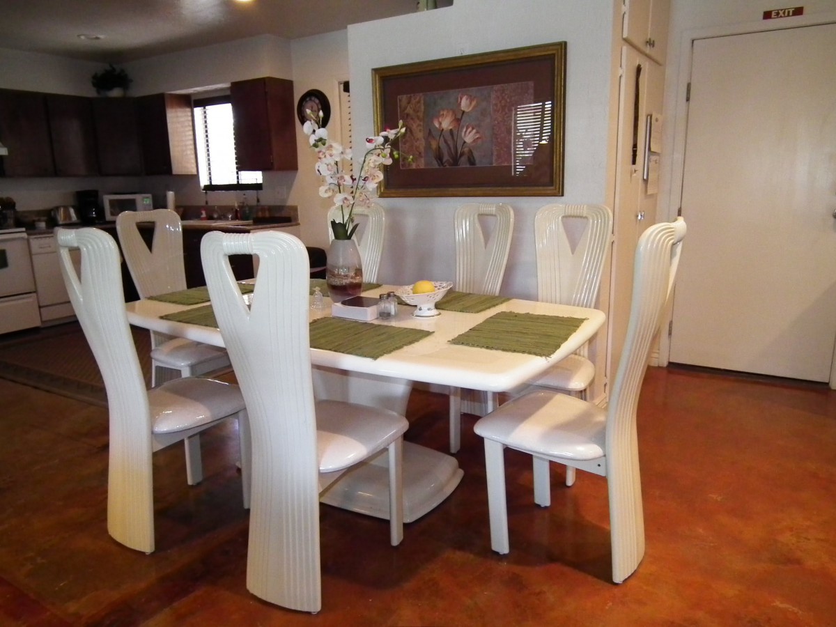 A modern dining room with a white table and matching chairs.