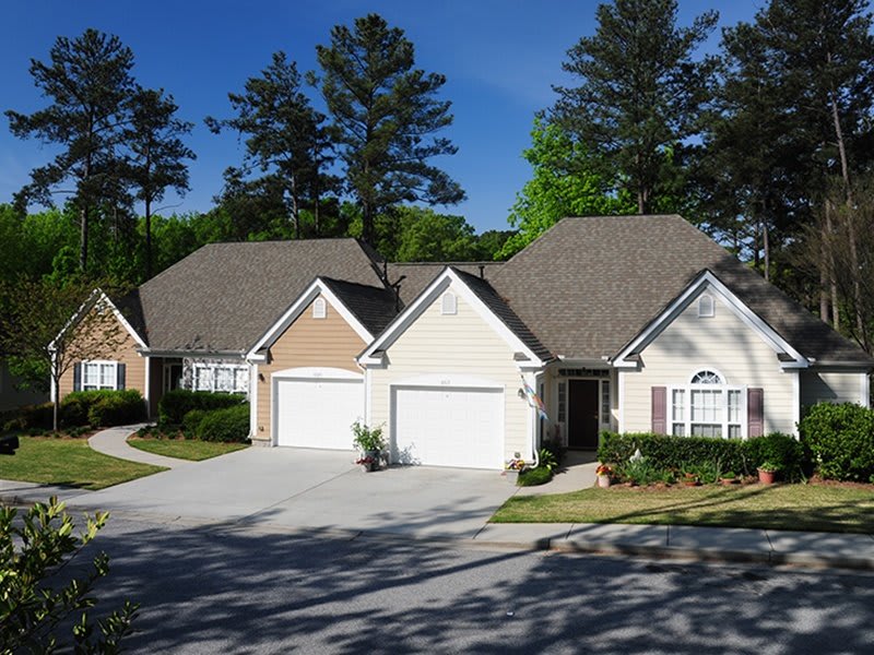 A suburban neighborhood featuring two adjacent houses with attached garages, surrounded by trees and landscaped grounds.