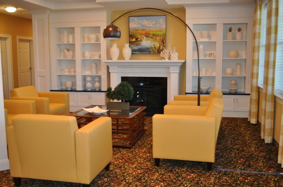 A cozy living room featuring yellow armchairs, a fireplace, and elegant decor elements.