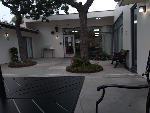 A serene outdoor area featuring benches and greenery in front of a modern building.