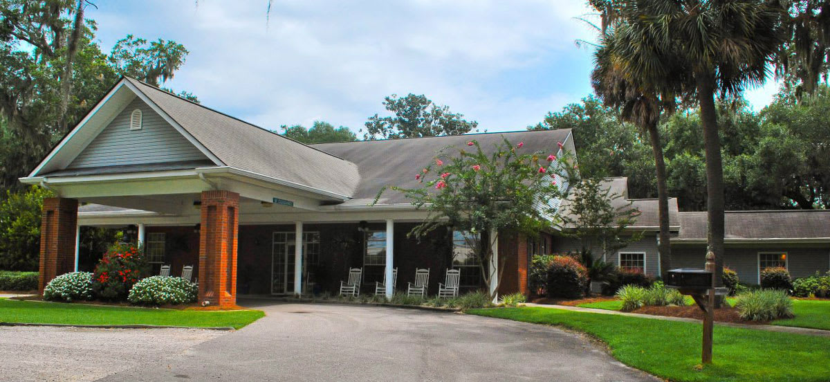 A residential building with a circular driveway and surrounding greenery.