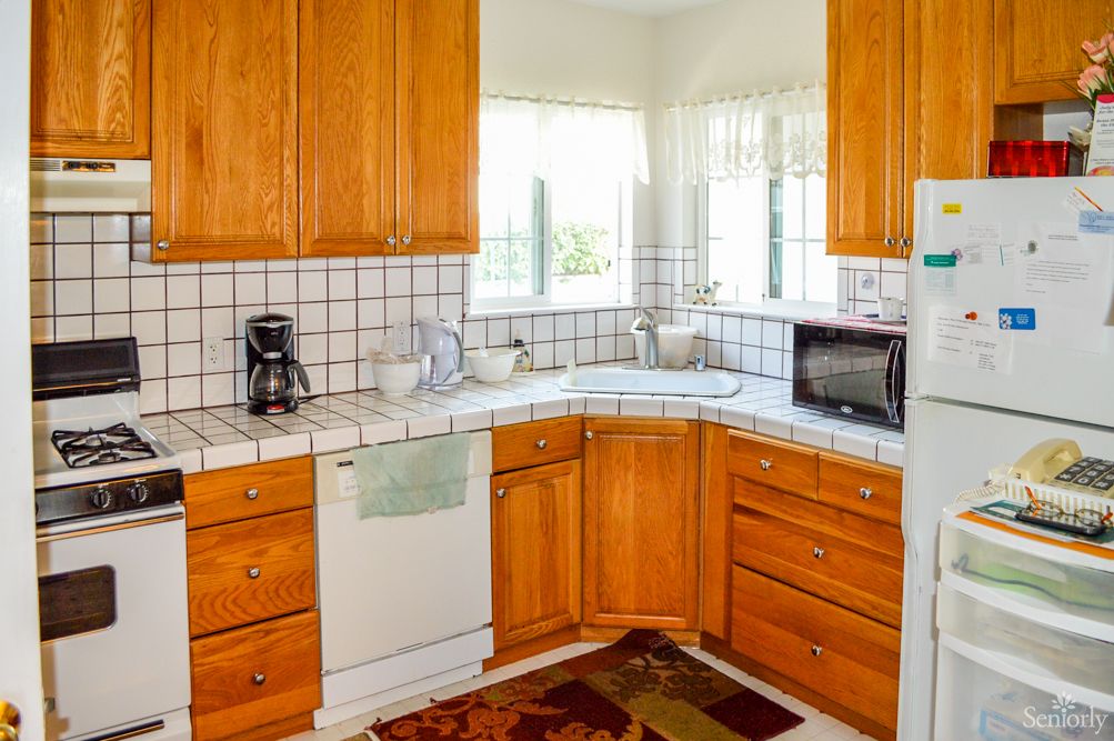 A cozy kitchen with wooden cabinets and a tile backsplash, featuring countertop appliances like a coffee maker and microwave.