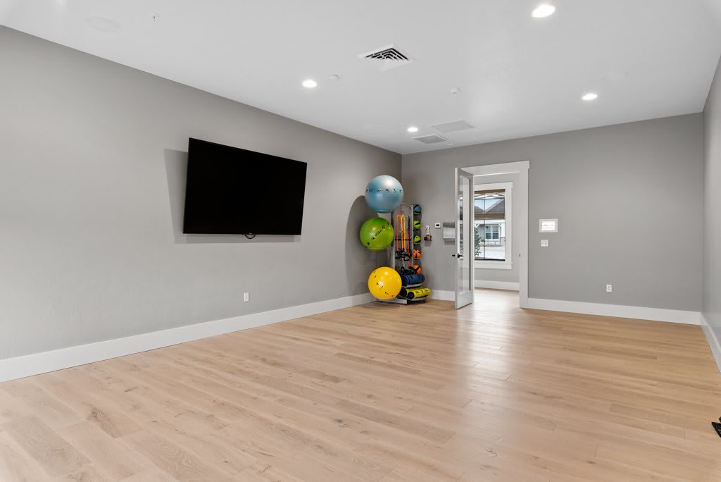 A spacious and modern room featuring a mounted television, exercise balls, and a minimalist design.