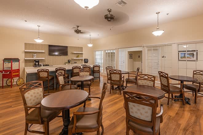 A well-lit dining area with multiple tables and chairs on a wooden floor.