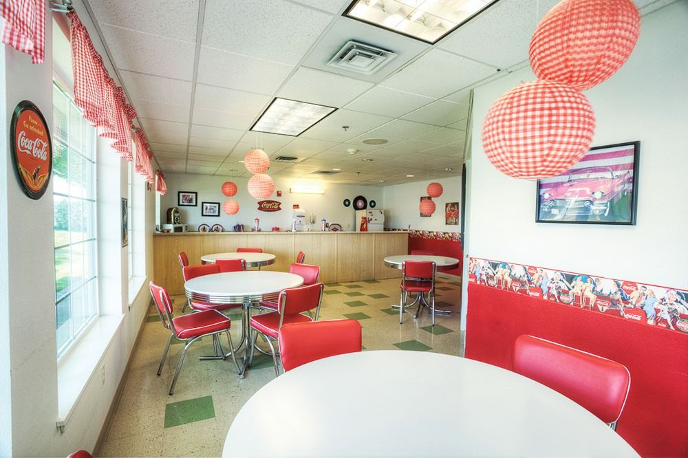 A retro-style diner interior with red and white decor, featuring round tables and chairs.