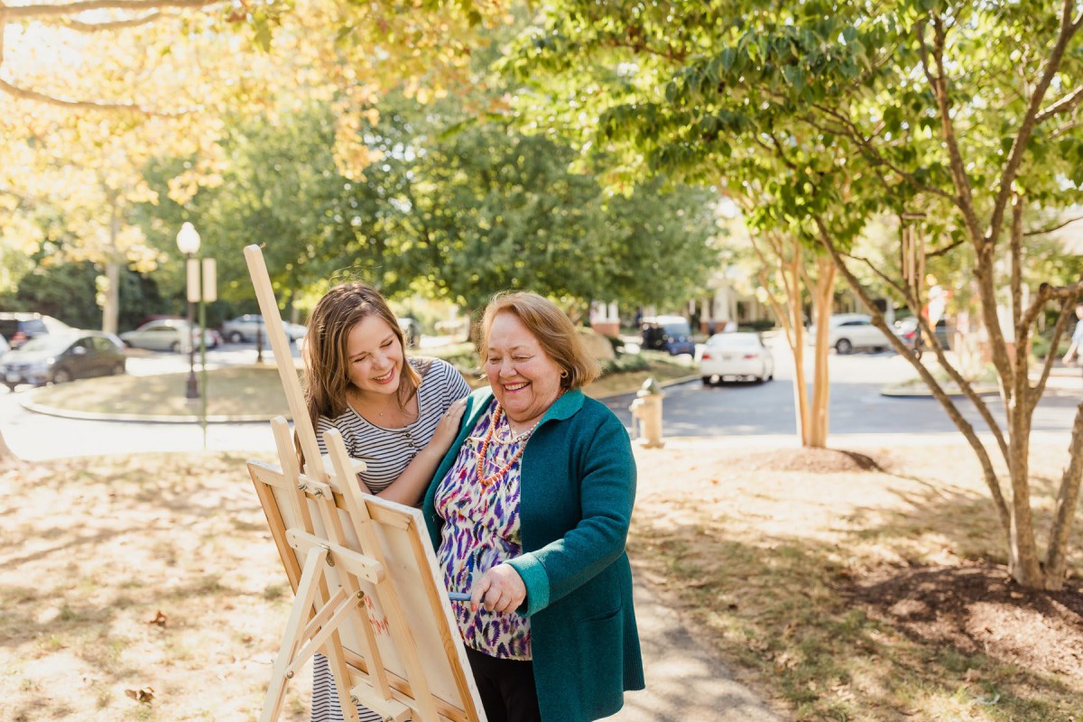 Two women enjoying an art display outdoors on a sunny day.