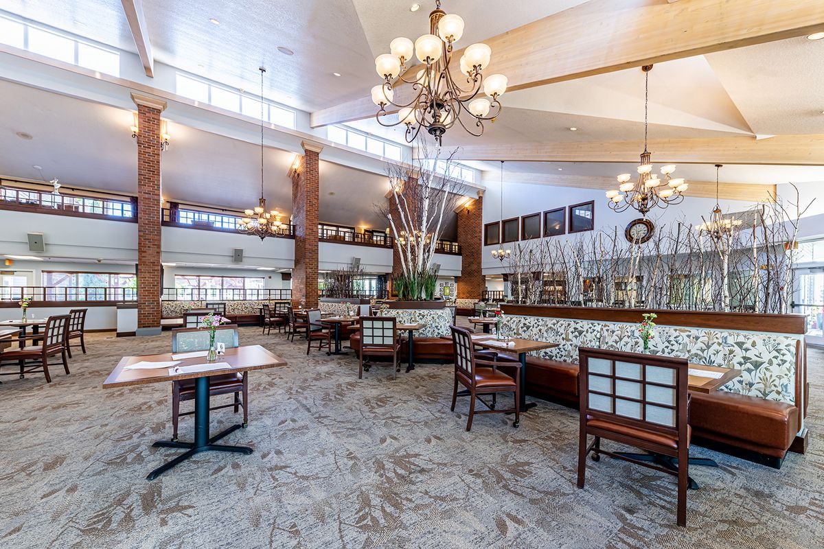 A spacious and elegantly designed restaurant dining area featuring chandeliers and neatly arranged tables.