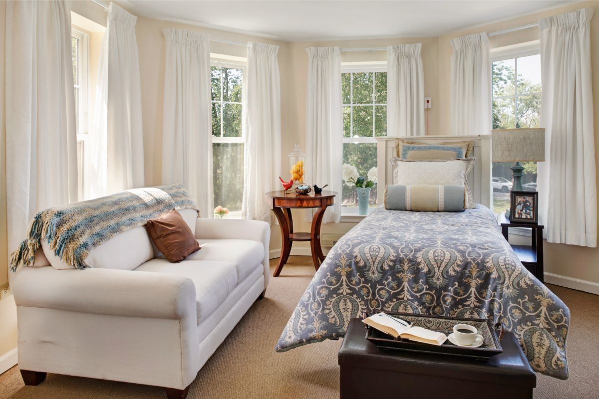 A cozy bedroom with large windows, a comfortable bed, and a plush sofa.