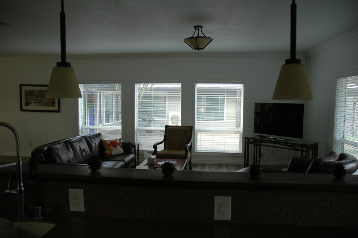 A cozy living room with a sofa, chair, and TV in front of large windows.