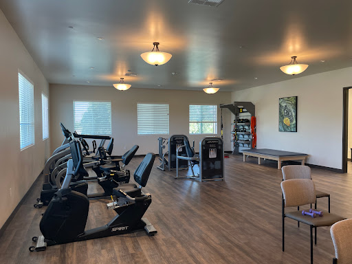 A spacious gym featuring modern exercise equipment and ample natural light.