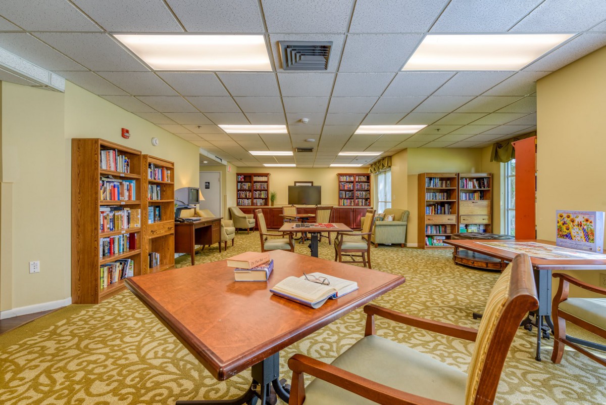 A cozy library interior with bookshelves, tables, and chairs.