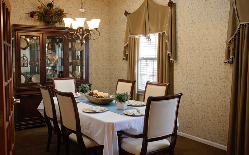 A elegant dining room with a table set for a meal, featuring a chandelier and classic decor.