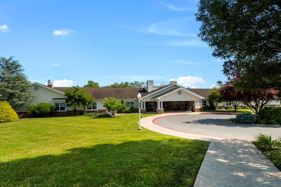 A spacious residential house with a large lawn and driveway under a clear blue sky.
